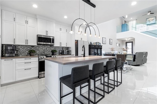 2215 Corales St, Mission, TX 78573 - kitchen with appliances with stainless steel finishes, light marble finish floors, white cabinets, a kitchen bar, and recessed lighting