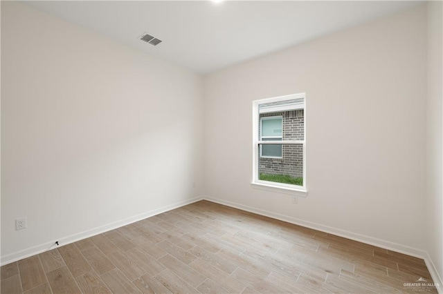 empty room featuring baseboards, visible vents, and light wood-style floors