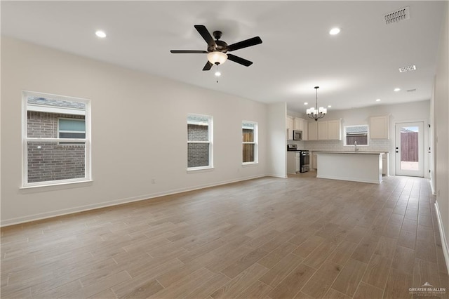 unfurnished living room with ceiling fan with notable chandelier, light wood-style flooring, visible vents, and recessed lighting