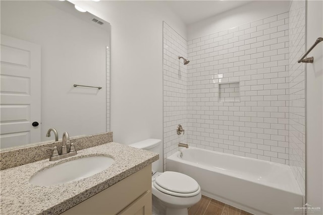 full bath with toilet, wood finished floors, visible vents, bathing tub / shower combination, and vanity