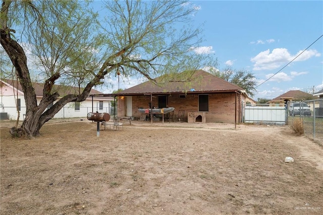 rear view of house featuring brick siding and fence