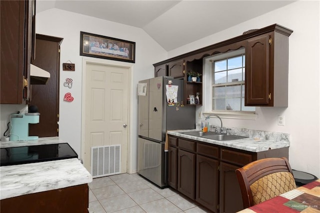 kitchen featuring light countertops, visible vents, freestanding refrigerator, a sink, and dark brown cabinetry