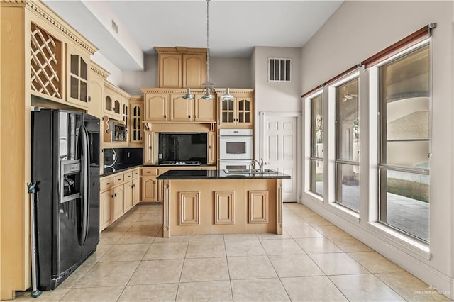 kitchen with sink, a center island, light brown cabinets, light tile patterned floors, and black appliances