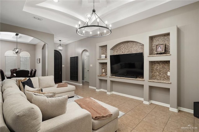 tiled living area with arched walkways, visible vents, a raised ceiling, and baseboards