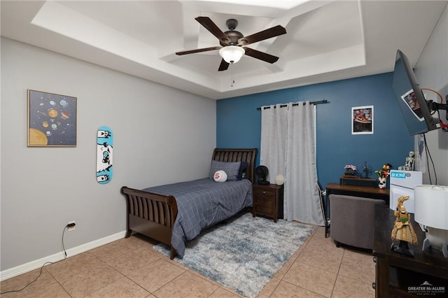 bedroom featuring tile patterned floors, ceiling fan, a raised ceiling, and baseboards