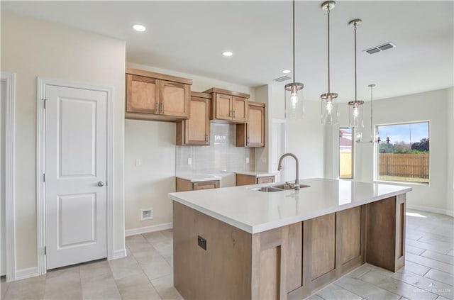 kitchen featuring backsplash, sink, pendant lighting, a center island with sink, and light tile patterned flooring