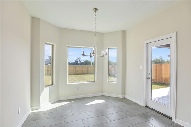 unfurnished dining area with a wealth of natural light, light tile patterned floors, and a notable chandelier