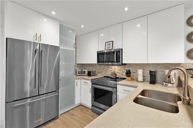 kitchen featuring modern cabinets, white cabinets, appliances with stainless steel finishes, and a sink