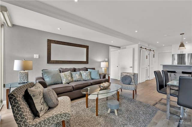 living room featuring a barn door, light wood-style flooring, baseboards, and recessed lighting