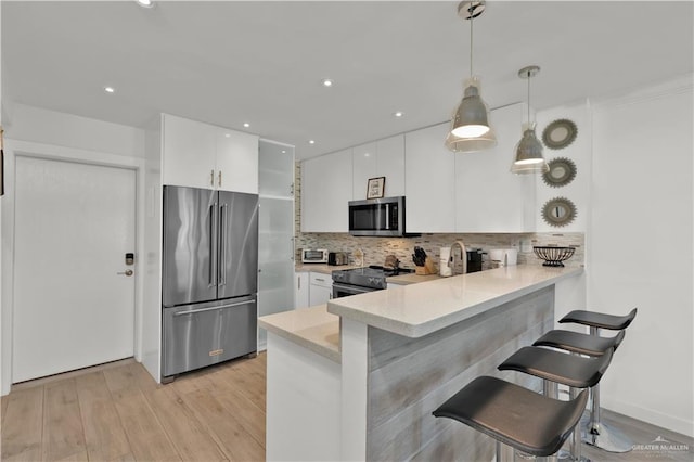 kitchen featuring white cabinets, appliances with stainless steel finishes, a breakfast bar area, and light countertops