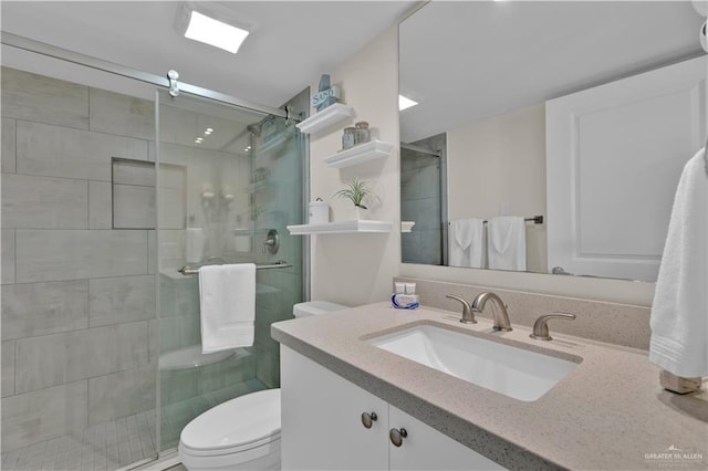 bathroom featuring a shower stall, toilet, and vanity