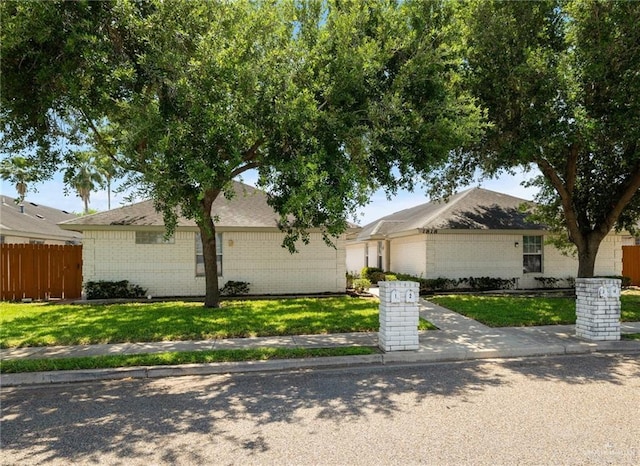 view of front of home featuring an attached garage, a front yard, fence, and brick siding