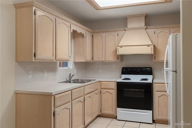 kitchen featuring freestanding refrigerator, light brown cabinetry, custom exhaust hood, a sink, and range with electric stovetop