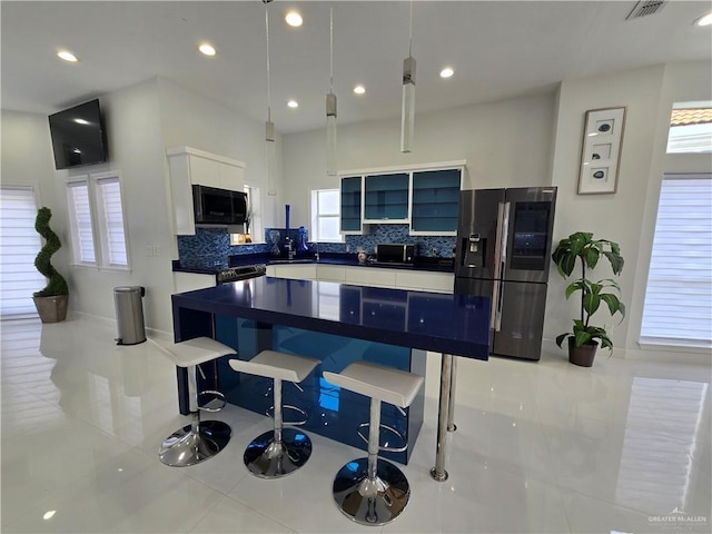 6503 Fountain Way S, Padre Island, TX 78597 - kitchen featuring stainless steel refrigerator with ice dispenser, black microwave, a breakfast bar, light tile patterned floors, and backsplash