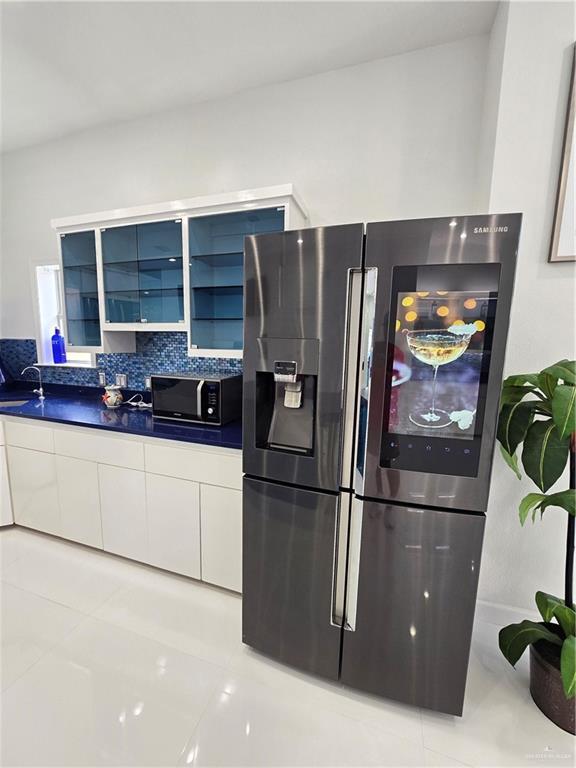 6503 Fountain Way S, Padre Island, TX 78597 - kitchen featuring stainless steel refrigerator with ice dispenser, black microwave, white cabinets, modern cabinets, and dark countertops