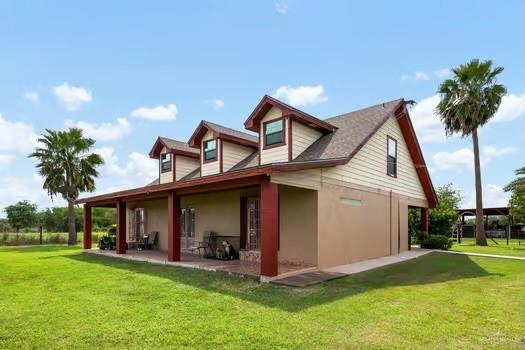 rear view of property featuring a lawn and a patio area