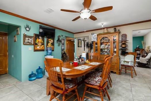 dining area with light tile patterned floors, ceiling fan, and ornamental molding