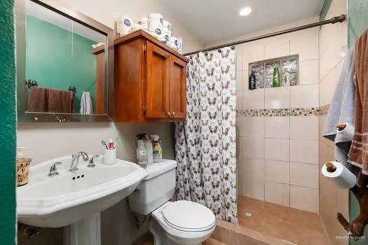 bathroom featuring tile patterned flooring, toilet, curtained shower, and sink