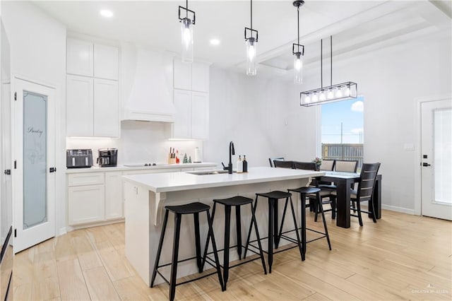 1801 Stardust Ln, Edinburg, TX 78541 - kitchen with premium range hood, an island with sink, light countertops, white cabinets, and a breakfast bar