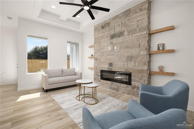 living room featuring a stone fireplace, ceiling fan, and light hardwood / wood-style floors