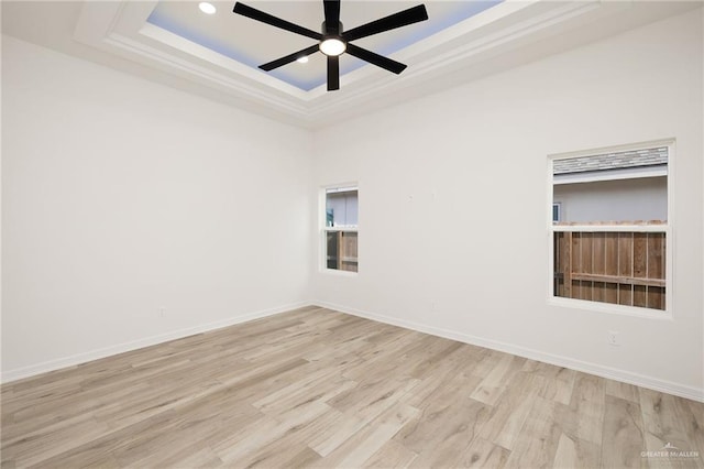 unfurnished room featuring a tray ceiling, light hardwood / wood-style flooring, and ceiling fan