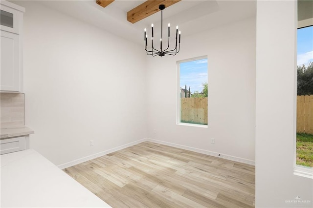 unfurnished dining area with beamed ceiling, light hardwood / wood-style flooring, a wealth of natural light, and a chandelier