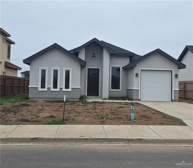 view of front of property with a garage, concrete driveway, fence, and stucco siding