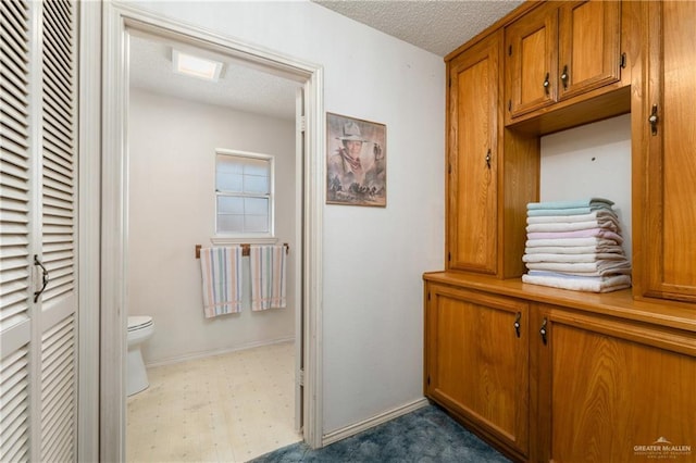 bathroom featuring tile patterned floors, toilet, baseboards, and a textured ceiling