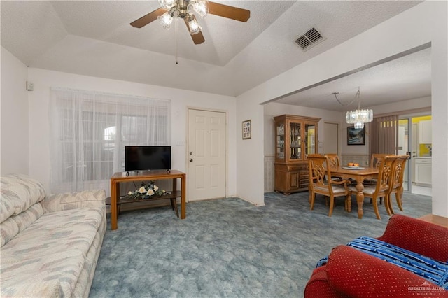 carpeted living room with a tray ceiling, ceiling fan with notable chandelier, visible vents, and a textured ceiling