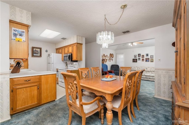 dining space featuring visible vents, a textured ceiling, wainscoting, and dark carpet