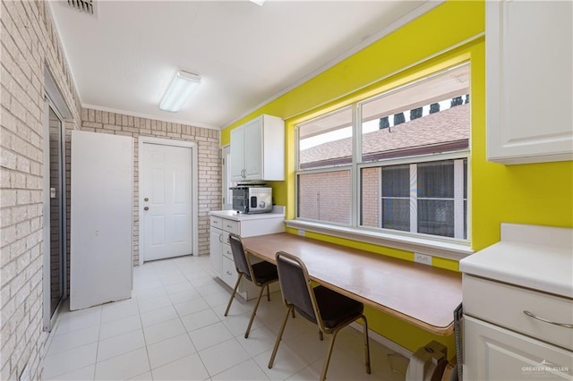 kitchen with stainless steel microwave, white cabinets, and brick wall