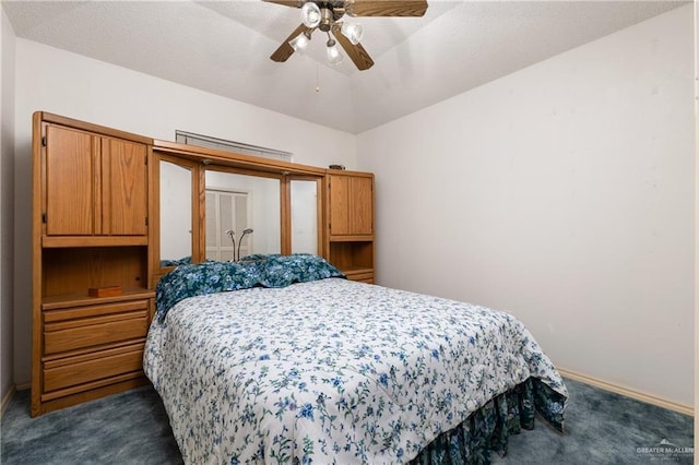 bedroom with dark colored carpet, baseboards, a textured ceiling, and a ceiling fan