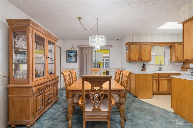 carpeted dining space featuring a sink, a textured ceiling, and an inviting chandelier