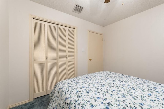 bedroom with visible vents, a closet, a textured ceiling, a ceiling fan, and dark colored carpet