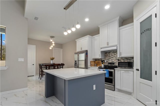 kitchen with pendant lighting, stainless steel appliances, white cabinets, a kitchen island, and decorative backsplash