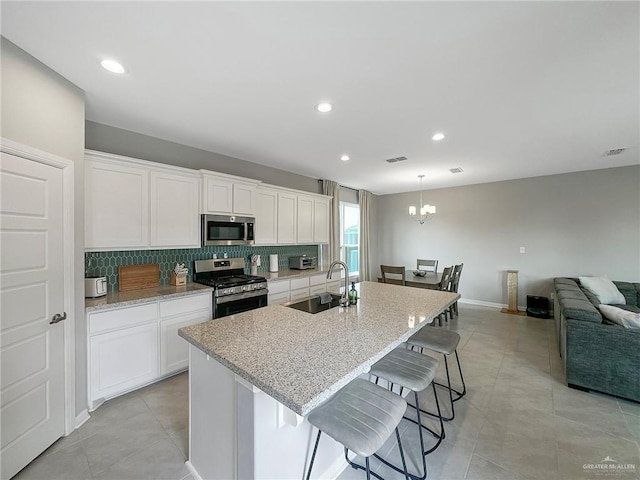 kitchen featuring stainless steel appliances, sink, a center island with sink, and white cabinets