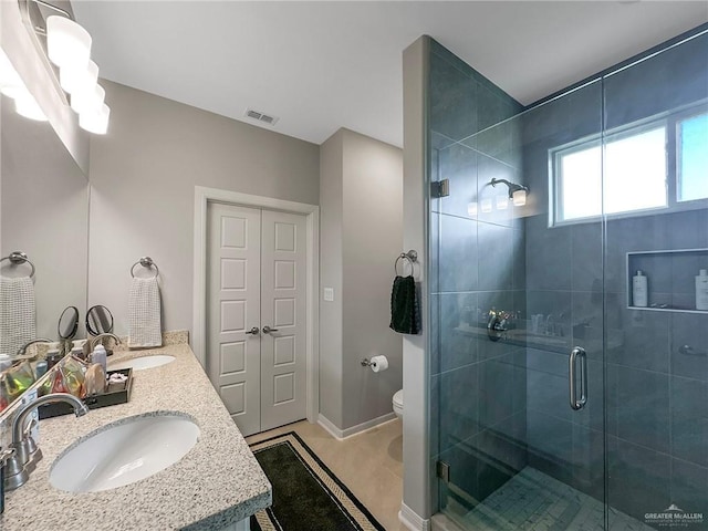 bathroom featuring vanity, toilet, and a shower with shower door