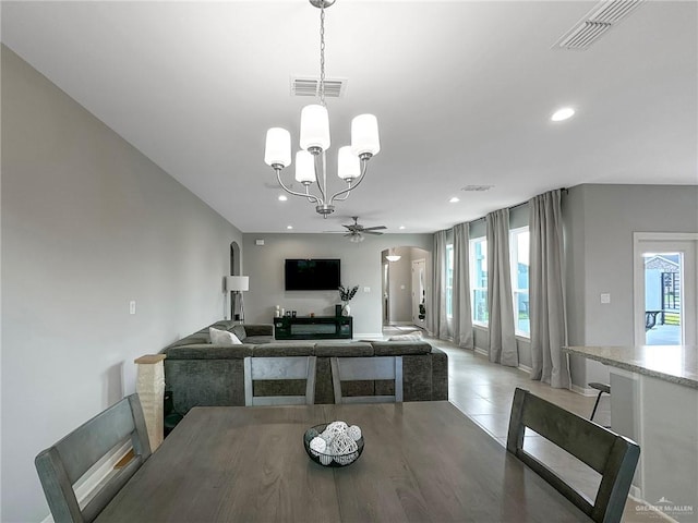 tiled dining area featuring ceiling fan with notable chandelier