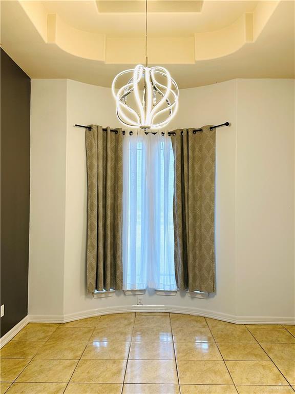 524 S Mile 2 W, Mercedes, TX 78570 - unfurnished dining area with light tile patterned floors, a chandelier, baseboards, and a tray ceiling
