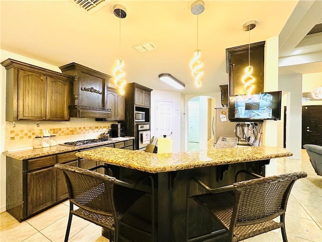 524 S Mile 2 W, Mercedes, TX 78570 - kitchen featuring visible vents, a kitchen bar, decorative backsplash, appliances with stainless steel finishes, and arched walkways