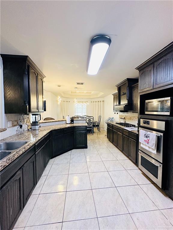 524 S Mile 2 W, Mercedes, TX 78570 - kitchen featuring visible vents, light tile patterned floors, a peninsula, stainless steel appliances, and a sink