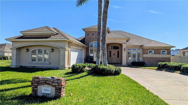 view of front of house with driveway, a garage, a front lawn, and stucco siding