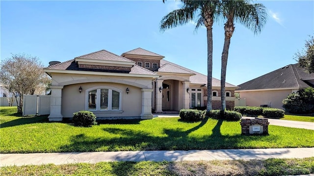 view of front of house featuring fence, a front lawn, and stucco siding