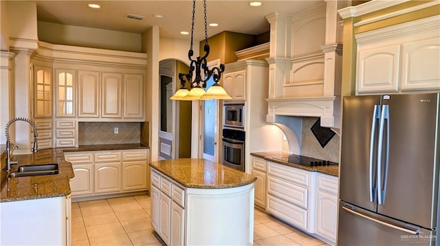 kitchen featuring visible vents, a center island, stainless steel appliances, pendant lighting, and a sink