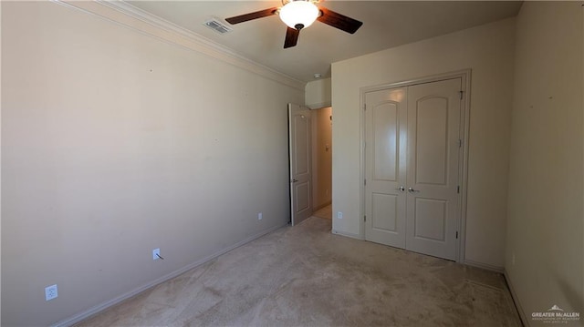 unfurnished bedroom featuring light colored carpet, visible vents, baseboards, a closet, and crown molding