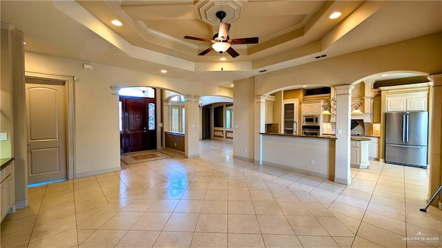 foyer featuring a tray ceiling, visible vents, light tile patterned flooring, ceiling fan, and baseboards