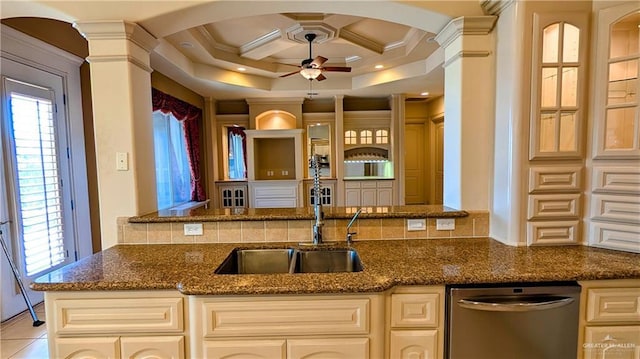 kitchen with decorative columns, dishwasher, ceiling fan, dark stone countertops, and crown molding