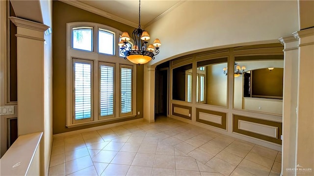 interior space featuring a wealth of natural light, crown molding, decorative columns, and an inviting chandelier