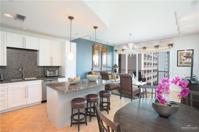 kitchen featuring dishwasher, sink, hanging light fixtures, tasteful backsplash, and white cabinetry