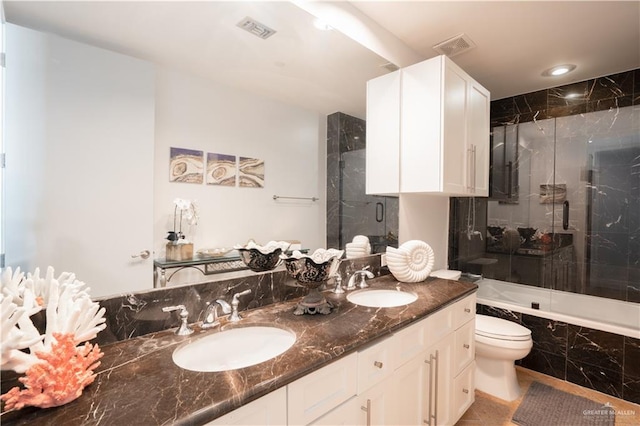 full bathroom with vanity, bath / shower combo with glass door, and toilet